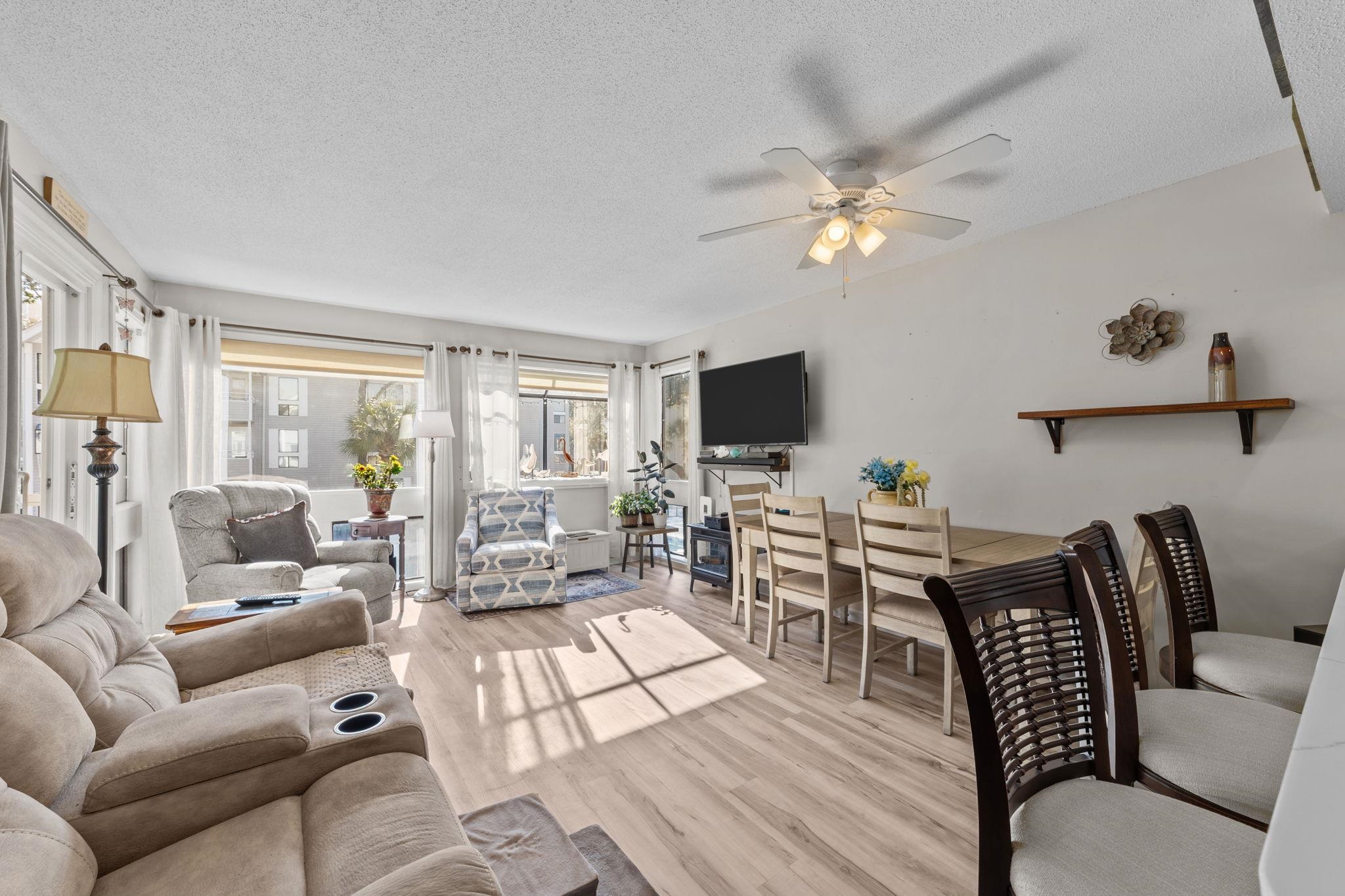 Living room with a textured ceiling, light wood finished floors, and a ceiling fan
