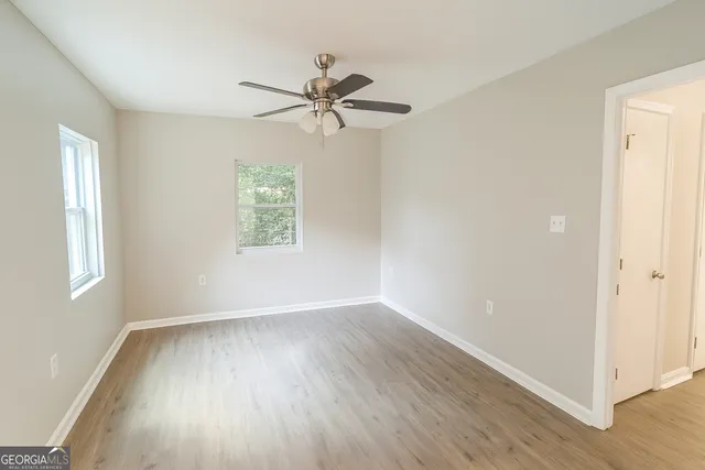 a view of an empty room with wooden floor and window