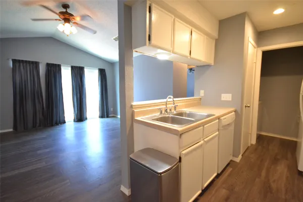 a kitchen that has a sink and a stove with wooden floor