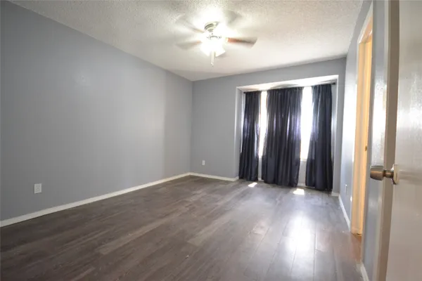 an empty room with wooden floor and a ceiling fan