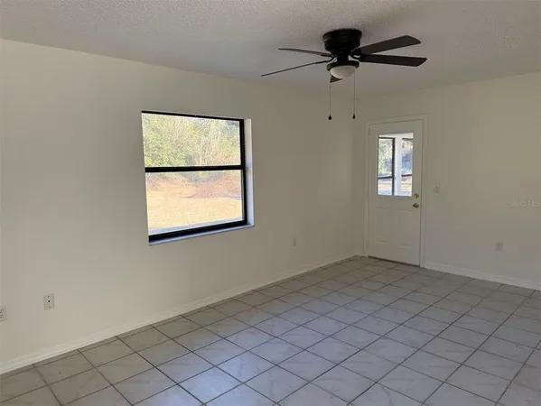 an empty room with windows and fan