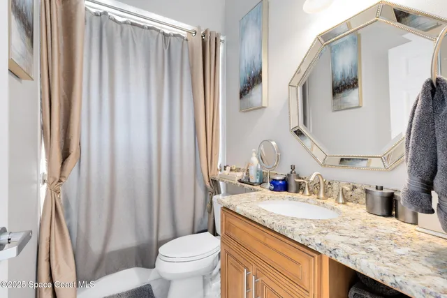 a bathroom with a granite countertop sink and a mirror with toilet