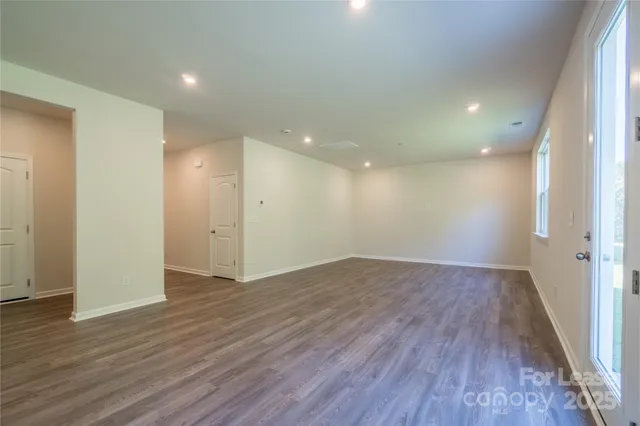 a view of an empty room with wooden floor and closet
