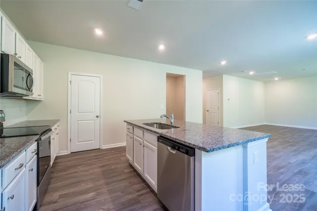 a kitchen with stainless steel appliances granite countertop a sink stove and cabinets