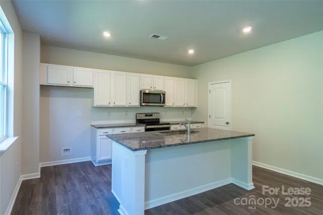 a kitchen with stainless steel appliances granite countertop a sink a stove a microwave a sink a refrigerator and cabinets