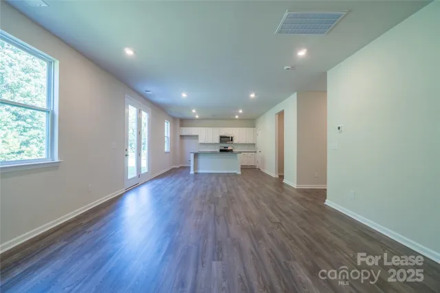 a view of a big room with wooden floor a cabinet and windows
