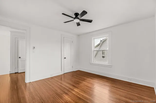 a view of empty room with wooden floor and ceiling fan