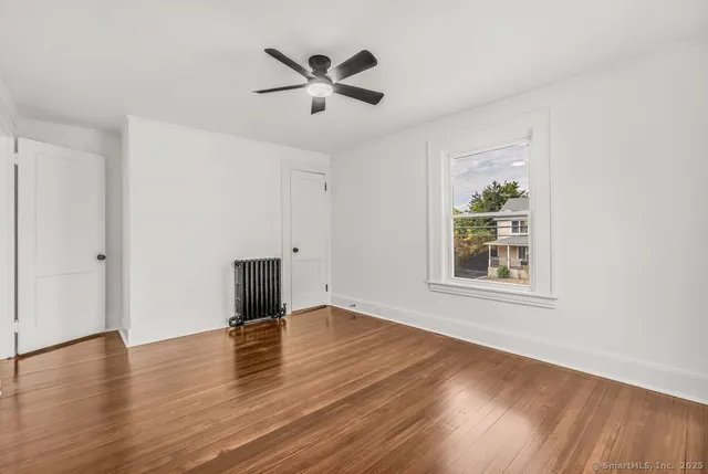 a view of empty room with wooden floor and window