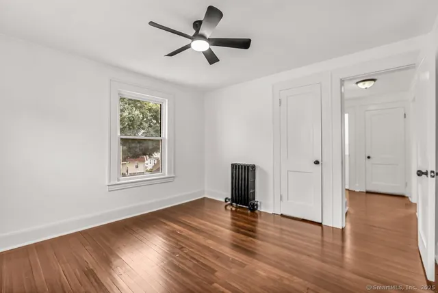 a view of empty room with wooden floor and fan