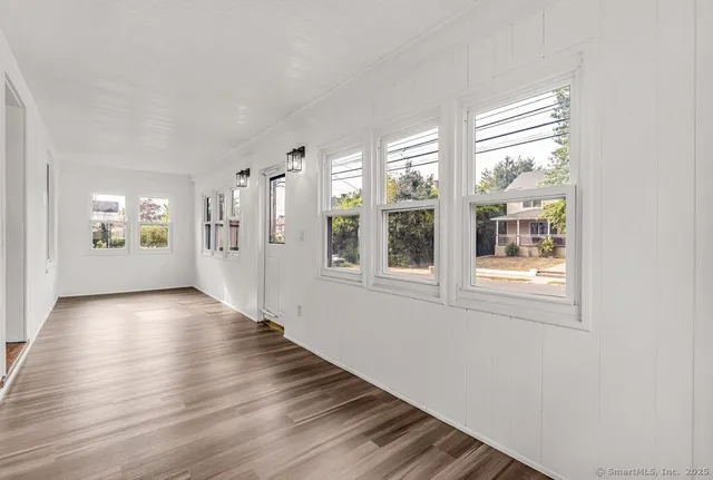 a view of an empty room with a window and wooden floor