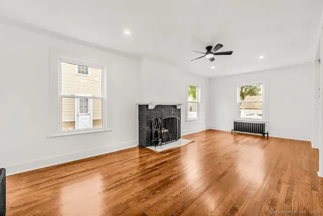 a view of empty room with fireplace and wooden floor