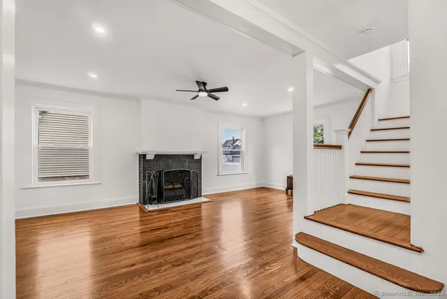 a view of an empty room with wooden floor fireplace and a window