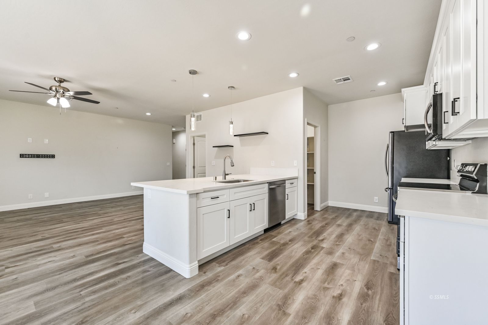 1031 West Church Avenue Ridgecrest, CA 93555 - Photo 11 of 49 a large white kitchen with wooden floor and a sink