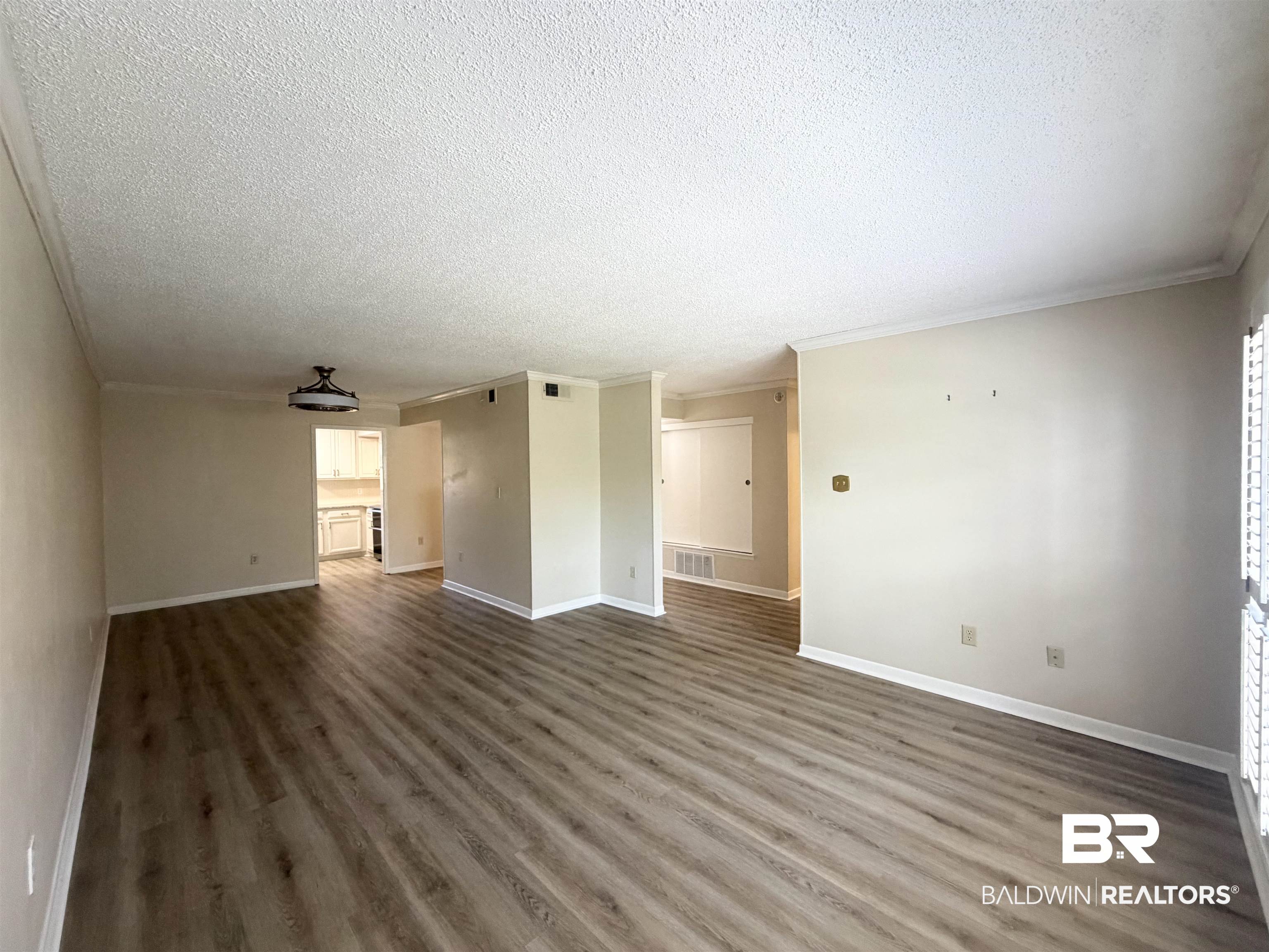 2901 Grant Street, Unit 902 Mobile, AL 36606 - Photo 33 of 35 Unfurnished living room featuring dark wood-type flooring, a textured ceiling, and crown molding