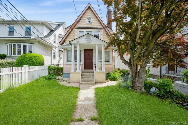 a view of a brick house with a big yard and large trees