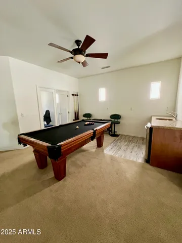 a living room with furniture pool table and a ceiling fan