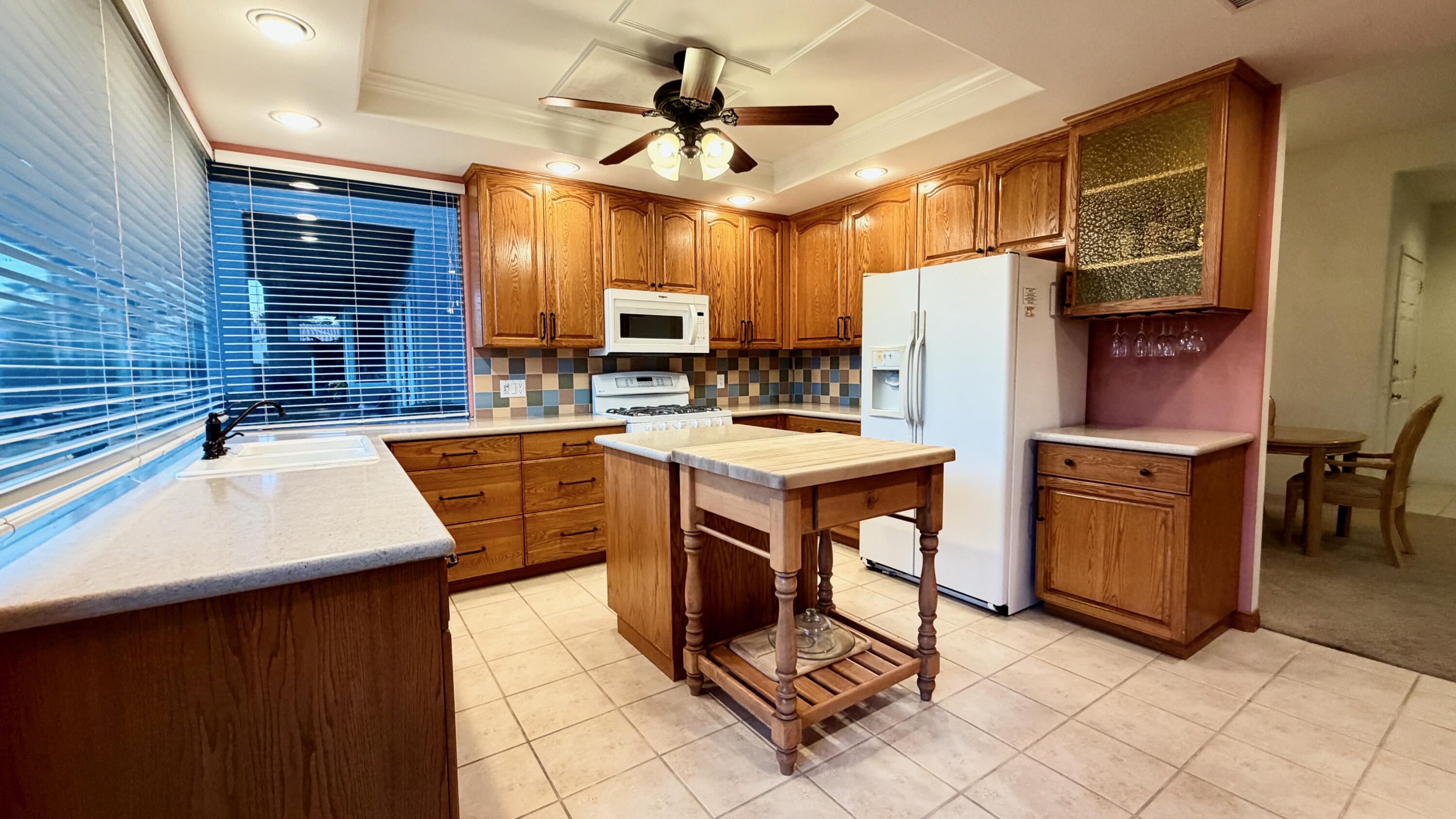 59 Oak Tree Drive Rancho Mirage, CA 92270 - Photo 7 of 22 a kitchen with stainless steel appliances granite countertop a sink a stove a refrigerator cabinets and chairs