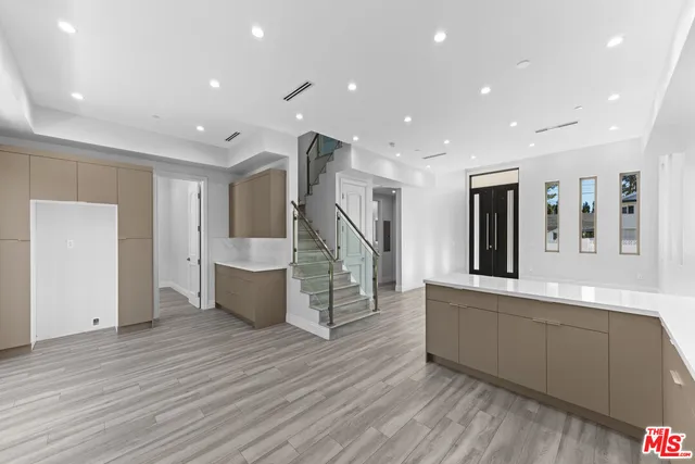 a view of an empty room and kitchen with sink wooden floor and windows