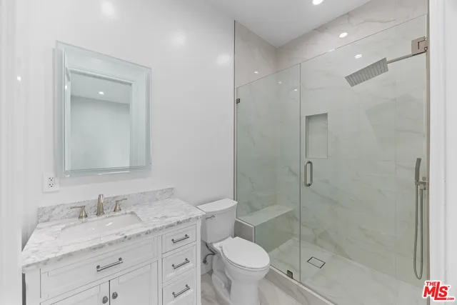 a bathroom with a granite countertop sink a toilet and shower