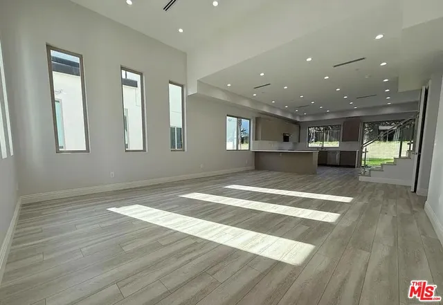 a view of an empty room with kitchen natural and wooden floor