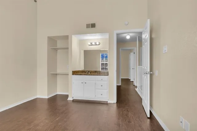 an empty room with wooden floor chandelier and windows