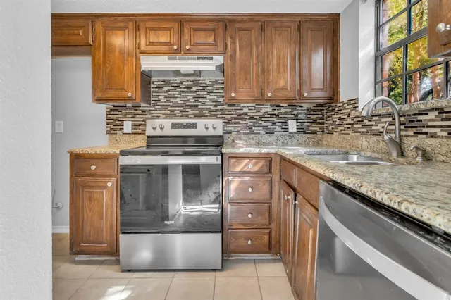 a kitchen with stainless steel appliances granite countertop a sink and a refrigerator