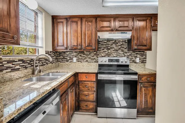 a kitchen with granite countertop a sink and a stove