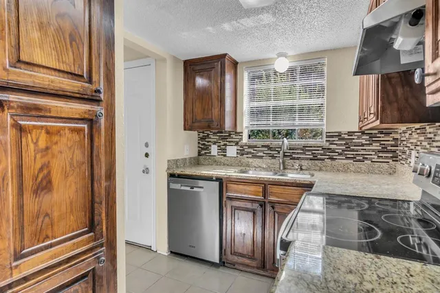 a kitchen with stainless steel appliances granite countertop a sink and a refrigerator