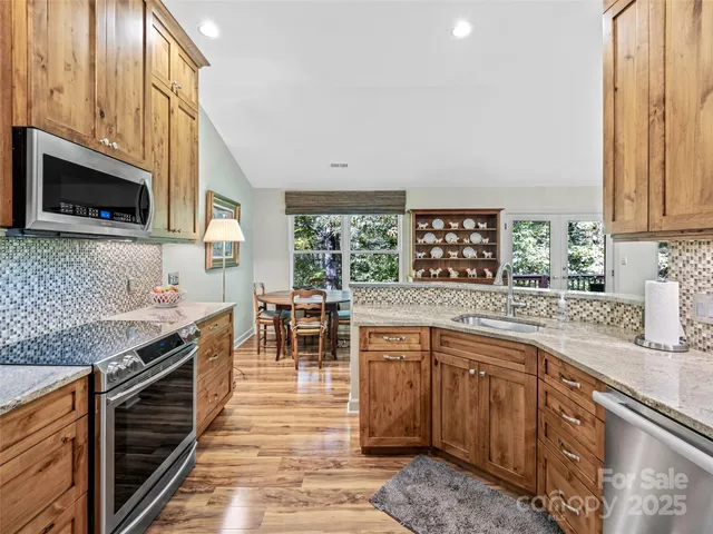 a kitchen with stainless steel appliances granite countertop sink stove top oven and cabinets