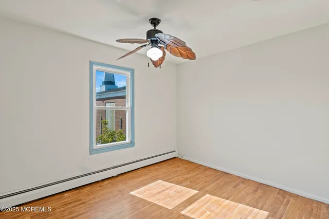 a view of empty room with wooden floor and fan