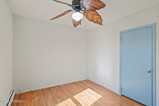 a view of a room with a ceiling fan and wooden floor