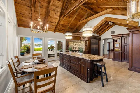 a view of kitchen with stainless steel appliances granite countertop dining table chairs cabinets and a sink