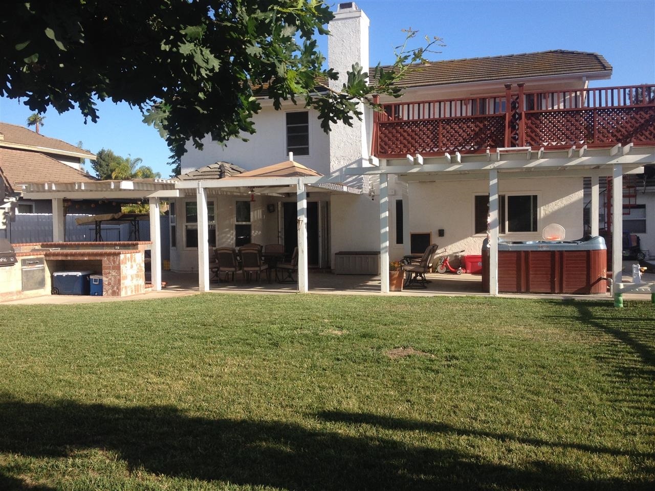 1418 Henshaw Road Oceanside, CA 92056 - Photo 20 of 25 Rearview from Backyard. The Hot Tub and builtin l shaped sitting area surrounding the outdoor fire pit the right. To the left you have a large area for an outdoor dining table an farther to the left you have a BBQ grill and bar seating.