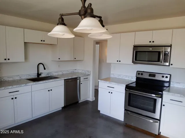 a kitchen with cabinets appliances a sink and a counter top