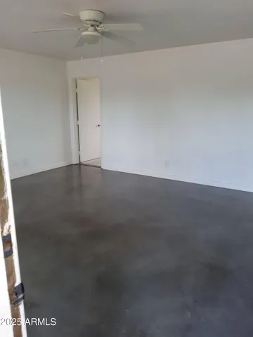 an empty room with a ceiling fan and window