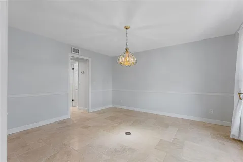 an empty room with windows and chandelier fan