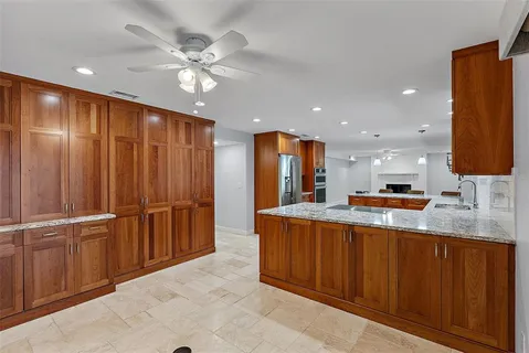 a large kitchen with stainless steel appliances kitchen island granite countertop a refrigerator and a stove top oven