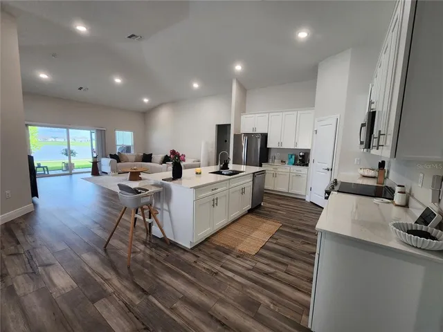 a large kitchen with lots of counter space a sink a window and stainless steel appliances