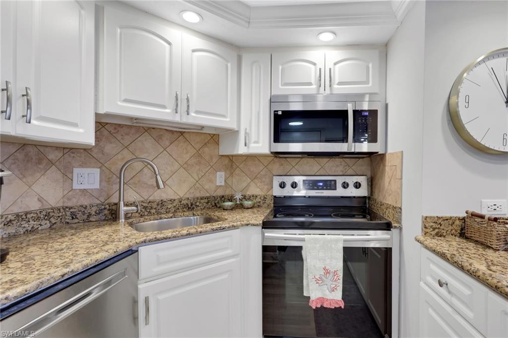 1 Bluebill Avenue, Unit 401 Naples, FL 34108 - Photo 14 of 35 a kitchen with granite countertop white cabinets and white appliances