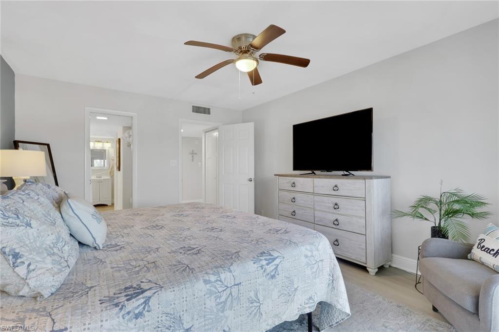 1 Bluebill Avenue, Unit 401 Naples, FL 34108 - Photo 19 of 35 a bedroom with a bed a flat screen tv and a dresser