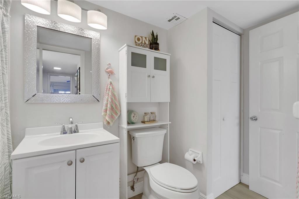 1 Bluebill Avenue, Unit 401 Naples, FL 34108 - Photo 22 of 35 a bathroom with a toilet a sink a mirror and vanity
