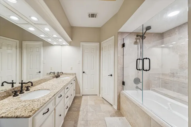a spacious bathroom with a granite countertop sink a mirror a bathtub and shower