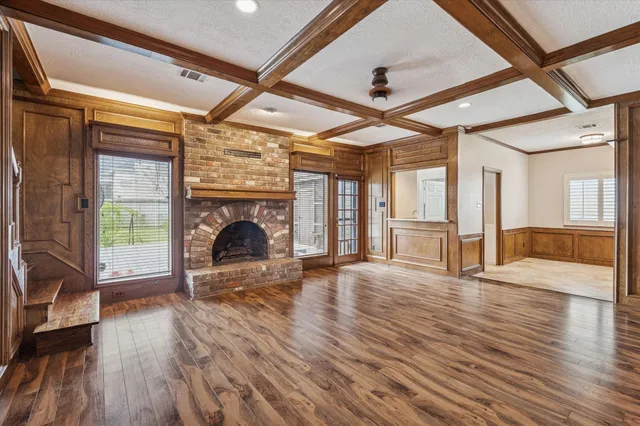 a view of an empty room with wooden floor fireplace and a window
