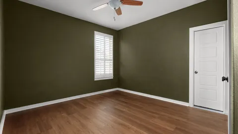 an empty room with wooden floor cabinet and windows