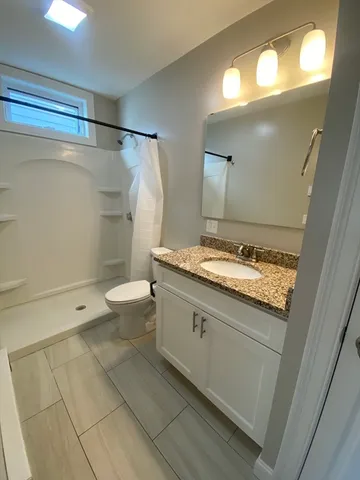 a bathroom with a granite countertop sink mirror vanity and toilet