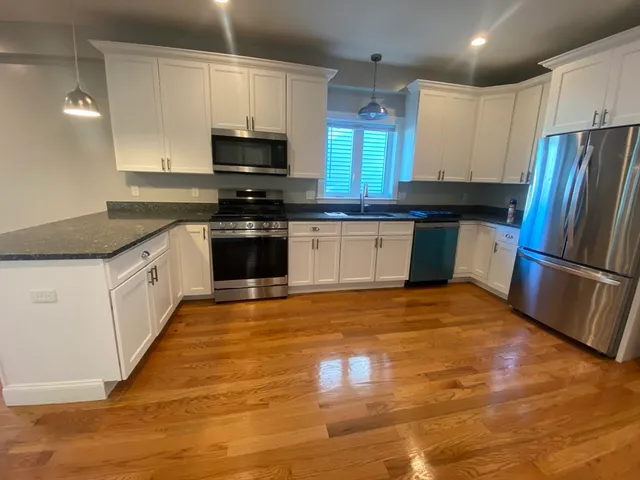 a kitchen with granite countertop a refrigerator and a stove top oven