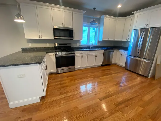 a kitchen with granite countertop a refrigerator and a stove top oven