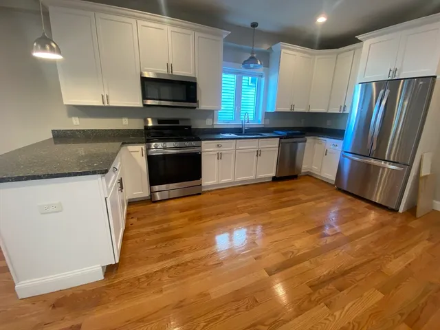 a kitchen with granite countertop a refrigerator and a stove top oven