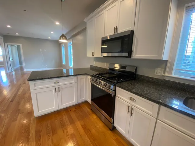 a kitchen with granite countertop white cabinets and black appliances