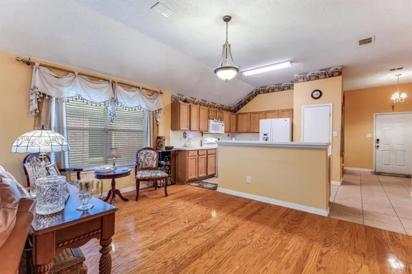 a living room with furniture kitchen view and a wooden floor